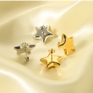 Polished star-shaped earrings in gold and silver finish on soft silk background