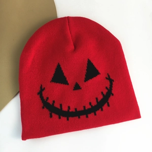 Macro detail of red knitted beanie featuring a black Halloween pumpkin face embroidery