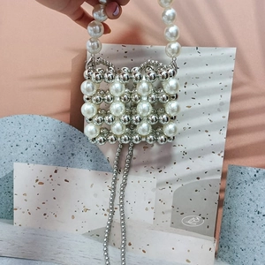 Detail of handmade beaded handbag with white pearls and silver beads in a square grid pattern