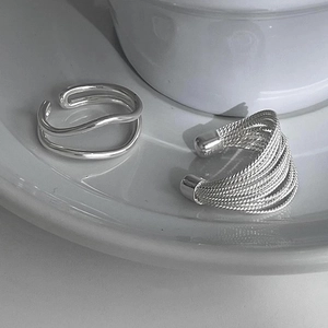 Detail of S925 sterling silver wavy open ring and textured ear cuff on ceramic