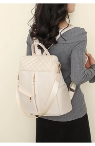 Detail of cream nylon backpack with diamond quilted stitching and gold zipper hardware