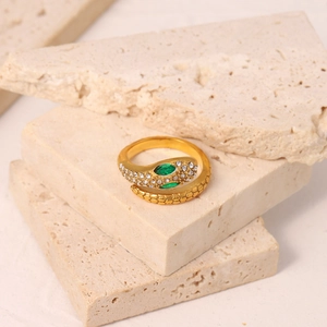 Detail of 18K gold plated snake ring with green zircon stones on natural stone