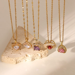 Detailed view of assorted 18k gold plated necklaces with colorful zircon pendants on stone