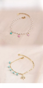 Detail view of pearl and gold bracelets with star charms and tree of life on silk
