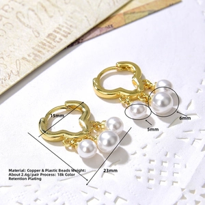 Close-up of heart-shaped 18k gold-plated earrings with elegant hanging white pearls