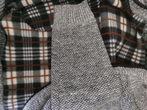 Close-up of grey chunky knit sweater showing ribbed cuffs and textured wool fabric