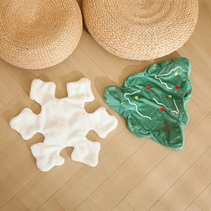 Plush Christmas snowflake and tree shaped pillows on light wood floor setting
