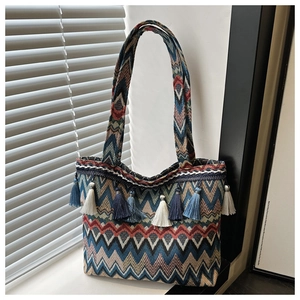 Detail of bohemian woven tote bag with wavy patterns and colorful decorative tassels