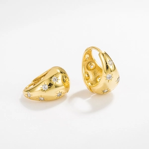 Close-up of gold-plated hoop earrings with white zircon starburst inlay and metallic texture