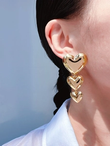 Gros plan de boucles d'oreilles cœur triple épaisseur en or montrant un éclat élégant
