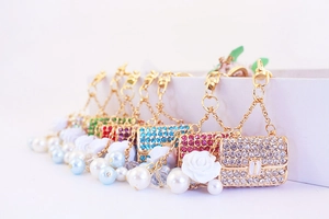 Detailed macro view of rhinestone-studded handbag keychains with pearls and white rose charms