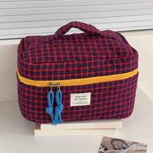 Close-up of quilted red and blue checkered toiletry bag with vibrant yellow zipper detail