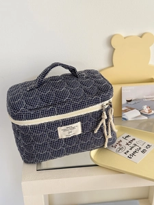 Navy blue quilted heart pattern cosmetic bag with top handle and white zipper closure