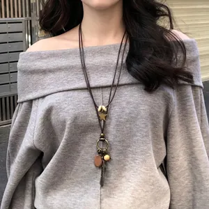 Close-up of ethnic star wood bead necklace with feather pendant and bronze ring charm