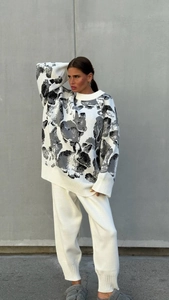 Close-up of knit texture showing grey rabbit pattern on a white long-sleeve sweater