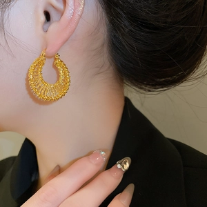 Close-up detail of 18k gold plated woven hollow hoop earring worn by a model