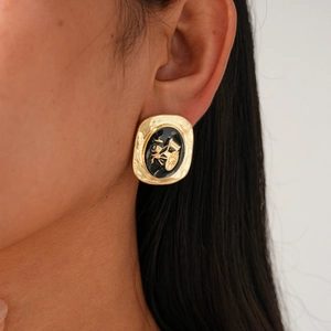 Détail de la boucle d'oreille ovale rétro en émail noir avec relief de calèche dorée