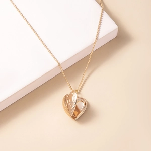Golden heart-shaped locket necklace with engraved floral pattern on a bead chain