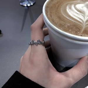 Adjustable silver butterfly ring with wave design worn by a person holding a coffee cup
