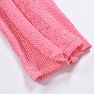 Détail de la texture en tissu seersucker rose avec ourlet élastique pour pantalon femme