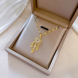 Dreamcatcher gold necklace with crystals on beige jewelry box display stand