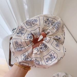 Close-up of cotton floral scrunchie showing the soft cream texture and blue print