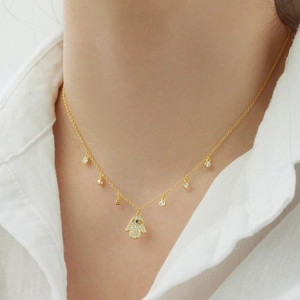 Détail du pendentif Main de Fatma dorée avec œil bleu et zircons sur la chaîne