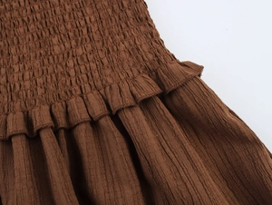 Detailed view of brown smocked fabric with elastic gathering and ruffled edge texture