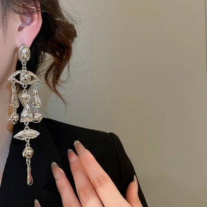 Detail view of silver tassel earrings with surreal abstract eye and lip elements