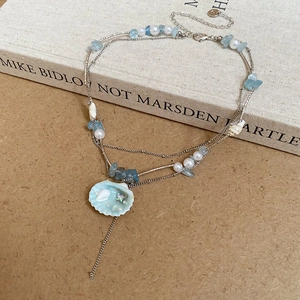 Detailed macro view of a silver shell pendant with mini pearls and blue sea stones