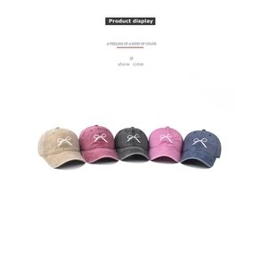 Detailed view of washed cotton baseball caps with embroidered bows in five colors