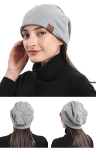 Detail of light gray knitted beanie with brown leather F&S tag and soft cotton texture