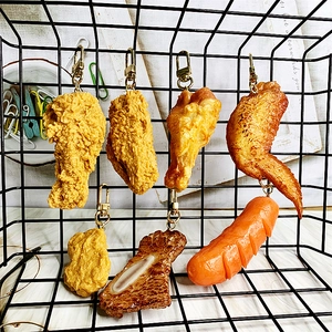 Detailopname van realistische voedsel-sleutelhangers met gebraden kip en biefstuk op rooster