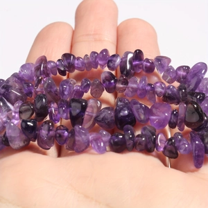 Detailed macro view of natural purple amethyst irregular crushed stone beads on hand