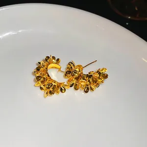 Elegant gold metal floral C-shape stud earrings with a polished petal design on a tray