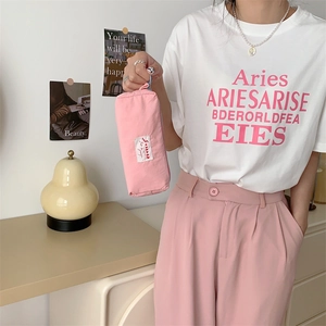 Pink macaron fabric makeup pouch held by model in casual lifestyle setting