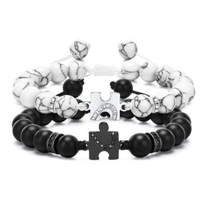 Detail view of black and white beaded couple bracelets with heart puzzle pendants
