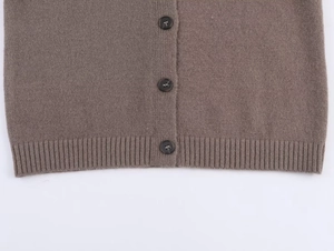 Détail d'un cardigan en maille marron avec boutons et texture d'ourlet côtelé