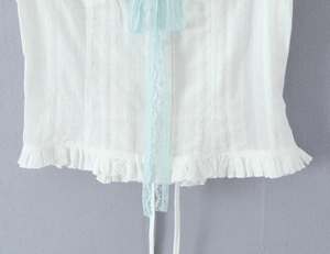 Close-up of white vertical ribbed fabric with light blue lace drawstring and ruffles