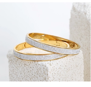 Close-up of gold-plated bangle set with pavé zircon crystals on a stone display