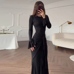 Détail d'une robe noire à manches longues avec lien à la taille et poignets volantés