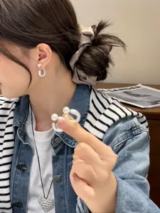 Detail showing elegant C-shaped pearl earrings and a 3D heart pendant necklace on a model