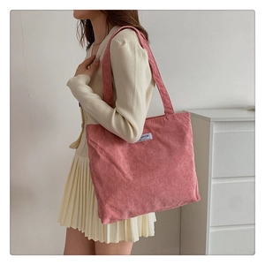 Detail of pink corduroy tote bag showing soft ribbed texture and fashion label on the side