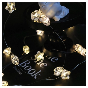 Macro shot of warm LED star and faceted oval beads on a delicate copper wire light string