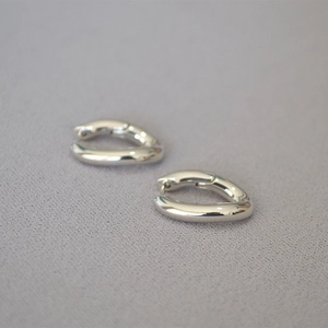 Vista macro de pendientes de aro en forma de U plateados con un acabado metálico pulido