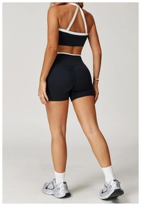 Detail van de high-waist yogashort en sportbeha met witte contrastranden op zwarte stof