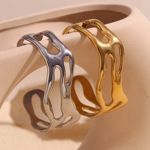 Minimalist 18K gold plated and silver wave hollow bangles on a beige sculpture