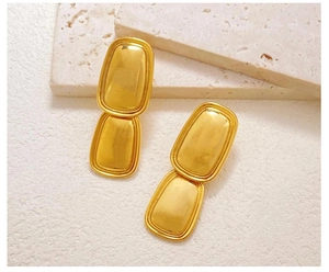 Detail of golden double-layer rectangular stainless steel stud earrings on a stone surface