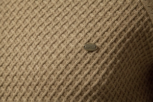 Macro detail of khaki knit sweater fabric with premium AIOPESON metal brand plaque