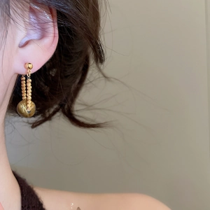 Primo piano di orecchini pendenti placcati oro 18k con catene di perline e sfere